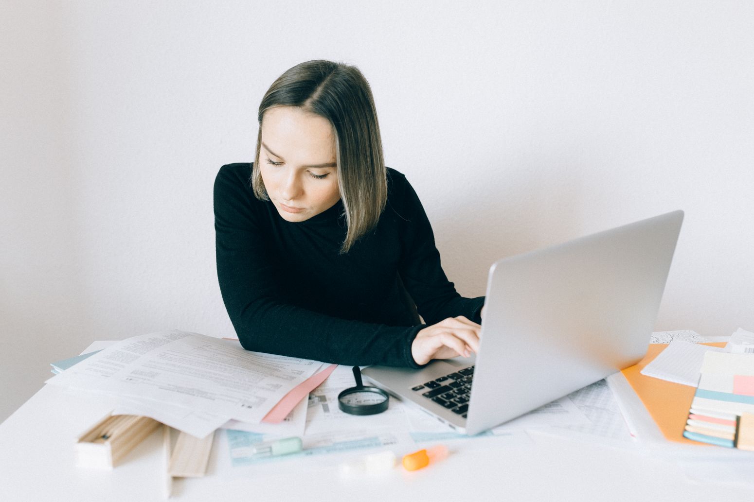 Professional woman reviewing business documents beside a laptop